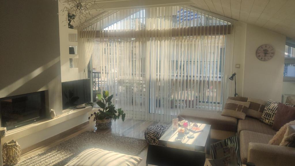 un soggiorno con divano e una grande finestra di Ηλιόλουστη σοφίτα Scandinavian αισθητικής. a Xánthi