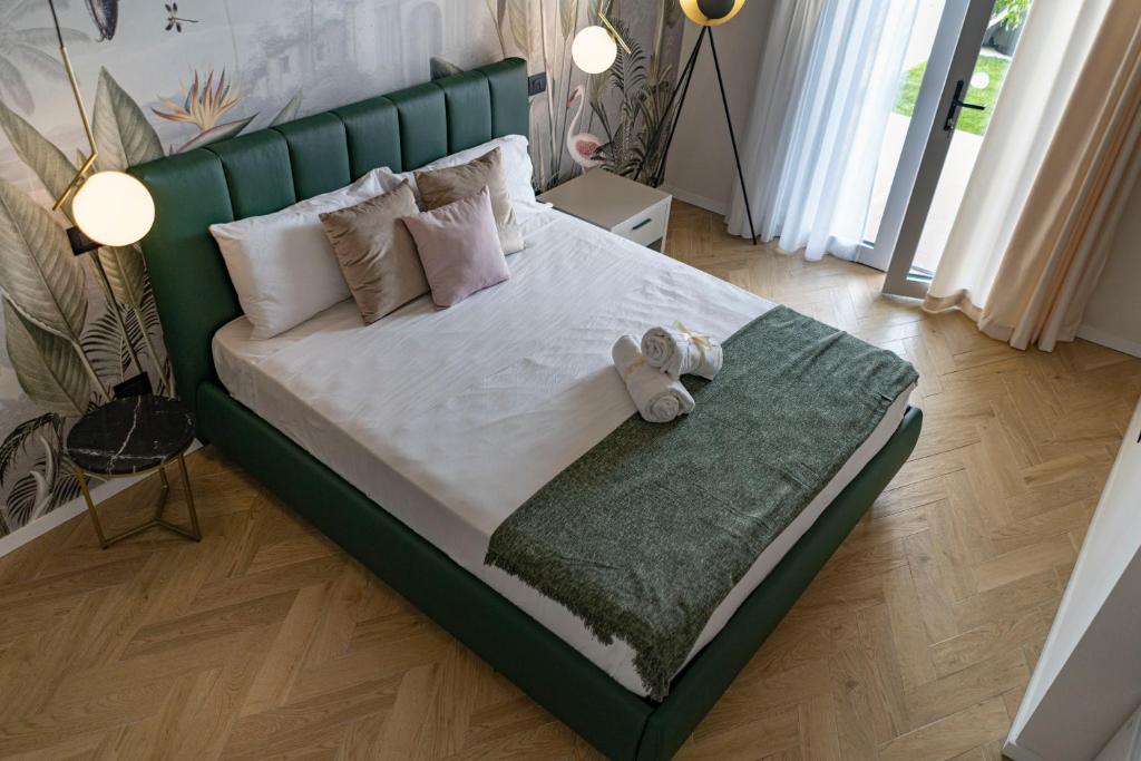 una cama verde con un oso de peluche sentado en ella en Ammare rooms, en Agrigento