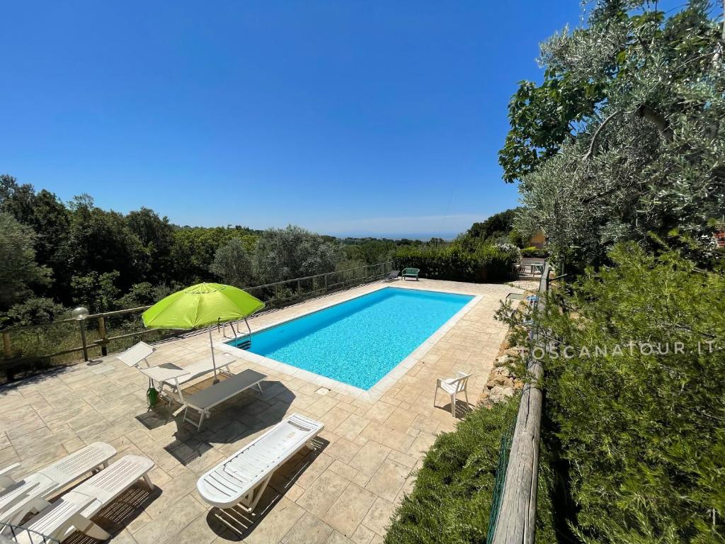 a swimming pool with chairs and a green umbrella at Casa Sophia con piscina - ingresso, giardino, barbecue e parcheggio privati by ToscanaTour in Guardistallo