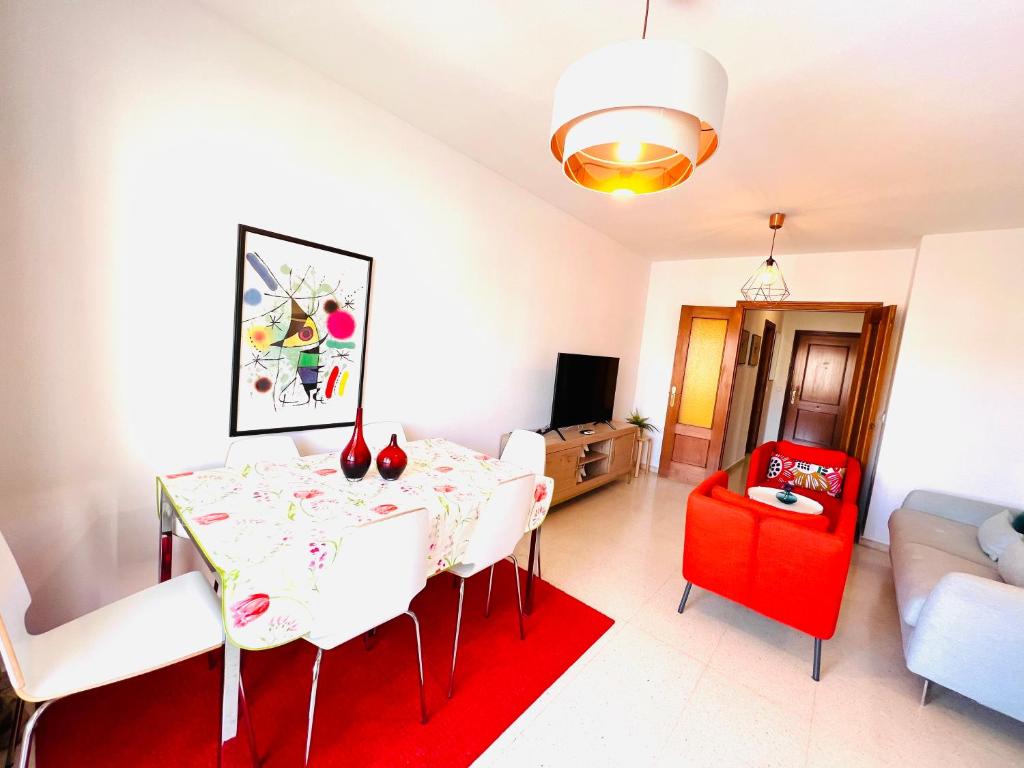 une salle à manger avec une table et une chaise rouge dans l'établissement Apartamento Rincón, Ideal para familias, à Cala del Moral