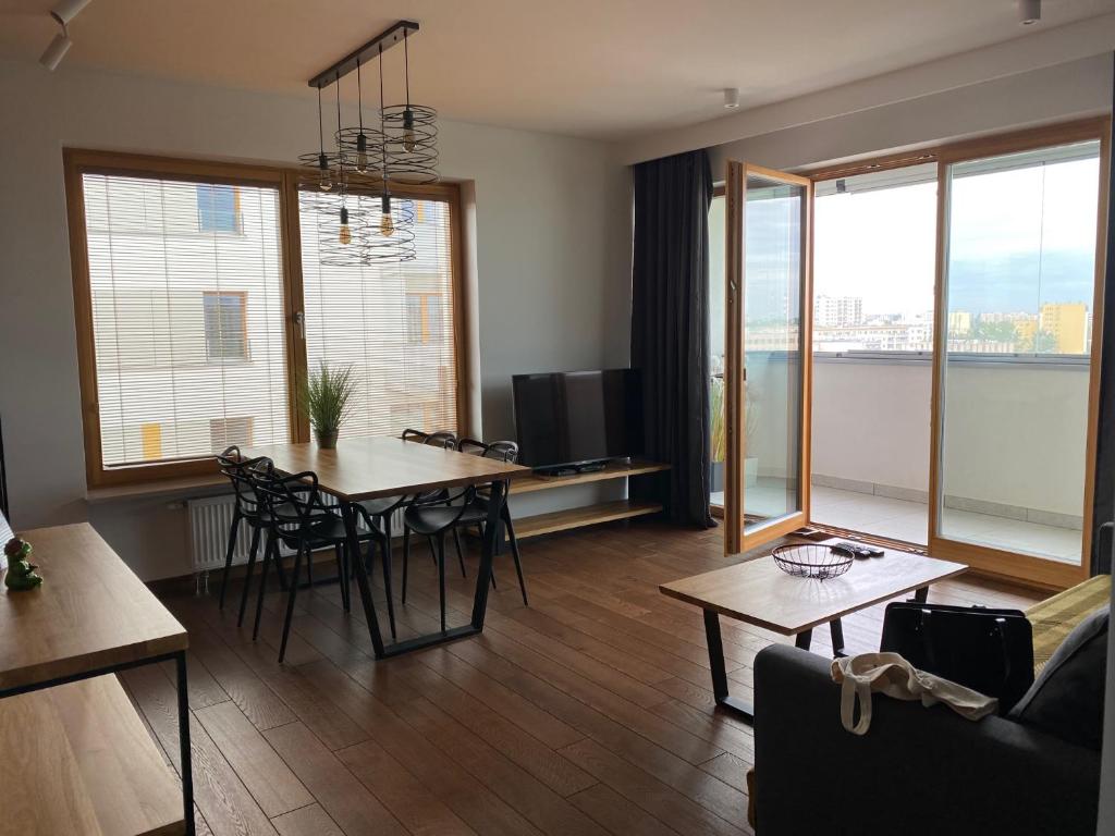 a living room with a table and chairs and windows at Apartament Rzekotka Zielona Dereniowa 60 in Warsaw