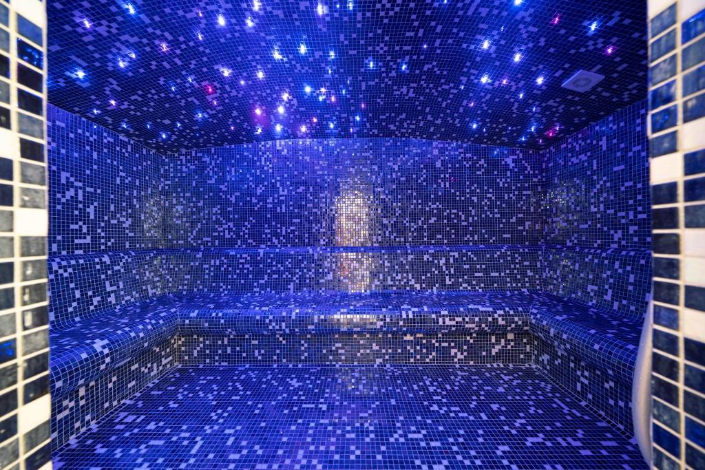 a blue tiled bathroom with a tub with blue lights at Hotel Millennium by Aycon in Budva