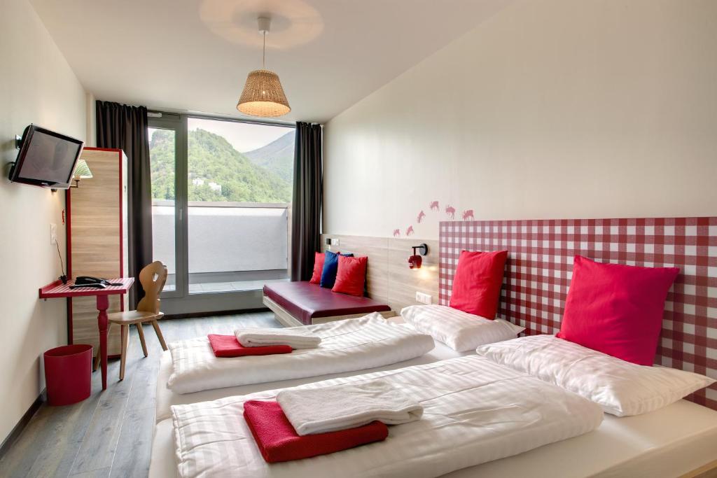 Habitación de hotel con 2 camas y almohadas rojas y blancas en MEININGER Hotel Salzburg City Center, en Salzburgo