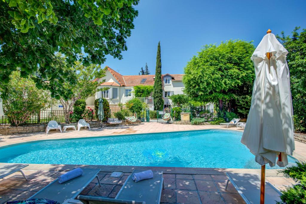 a swimming pool with an umbrella next to a house at Logis Hotel Le Blason de Provence in Monteux