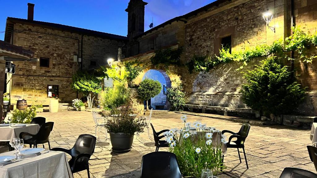 un patio con mesas y sillas frente a un edificio en La Posada Del Santuario en Nava de Santullán