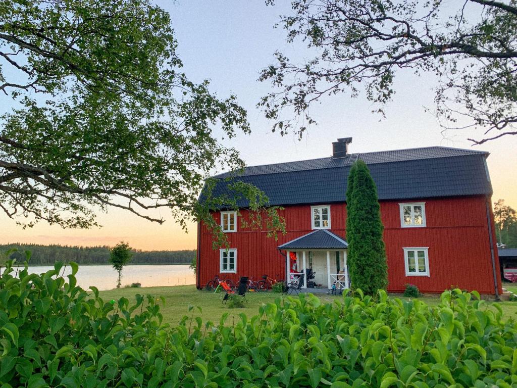 a red barn on the shore of a lake at Holiday home Tussered Hacksvik in Håcksvik