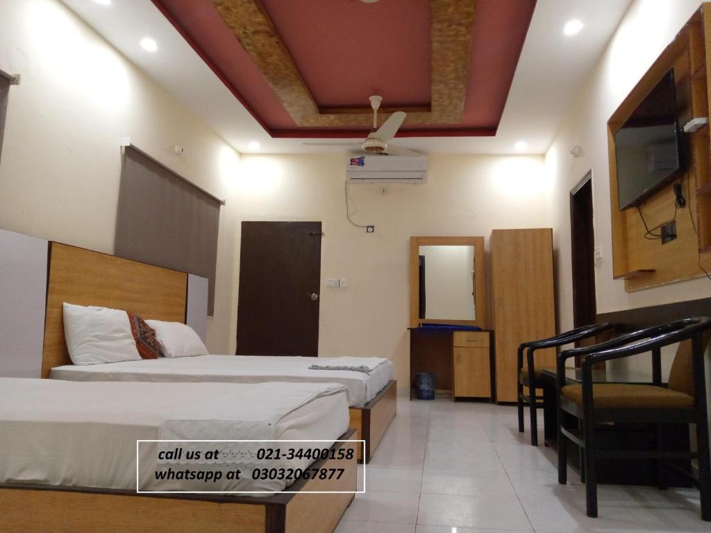 a hotel room with two beds and a tv at Pearl Cottage Guest House in Karachi