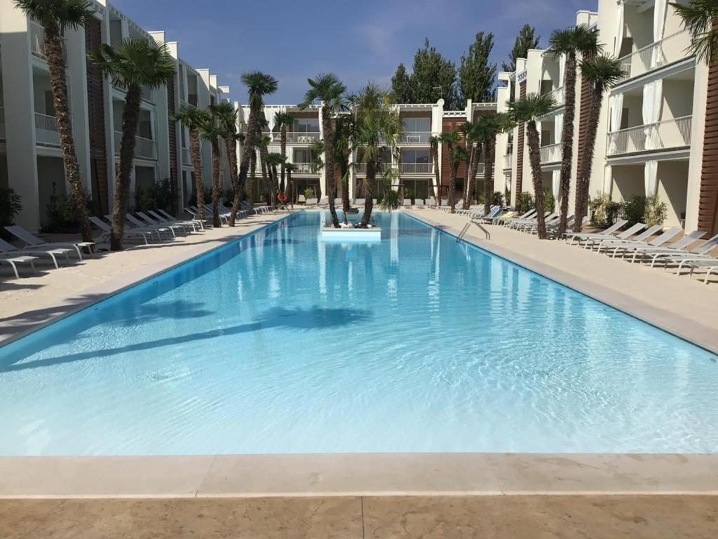 una gran piscina con palmeras y edificios en Residence Wave Plus, en Lido di Jesolo
