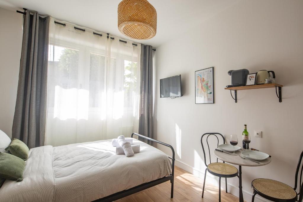 1 dormitorio con cama, mesa y ventana en Les Studios du Parc Bordelais - Le Sommelier, en Le Bouscat
