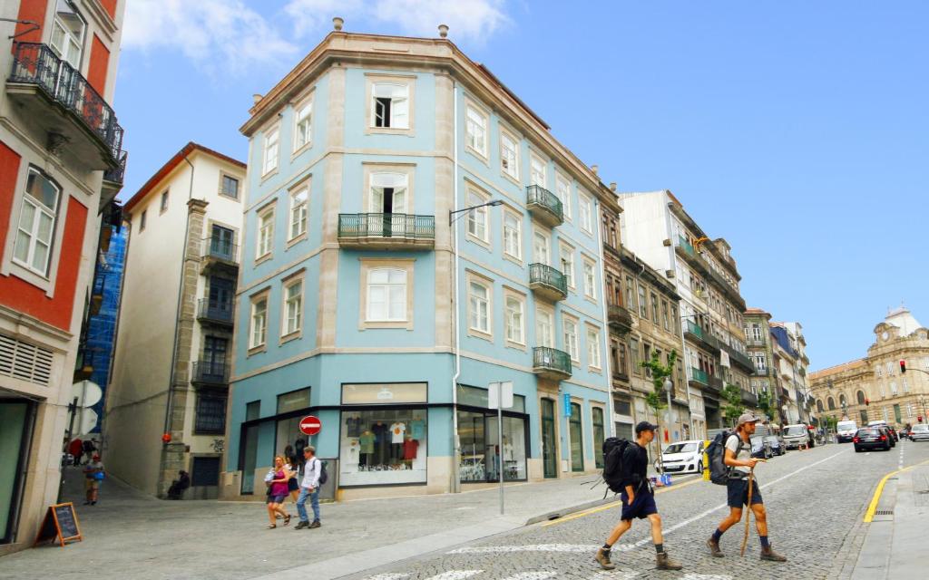 un grupo de personas cruzando una calle frente a un edificio azul en Best Guest Porto Hostel, en Oporto