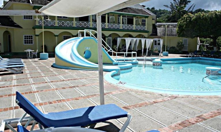 a large swimming pool with a slide in it at Private 2 Bedroom Beachfront Penthouse Condo Ocho Rios, Jamaica in Ocho Rios