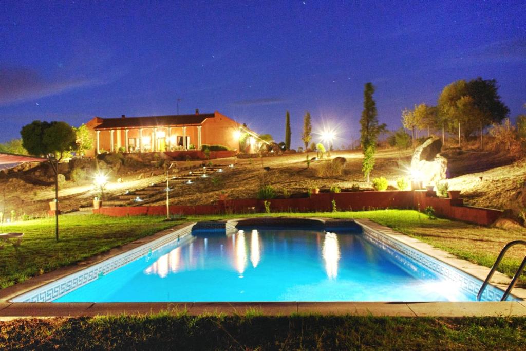 a swimming pool in front of a house at night at Casa Rural Romana in Don Álvaro