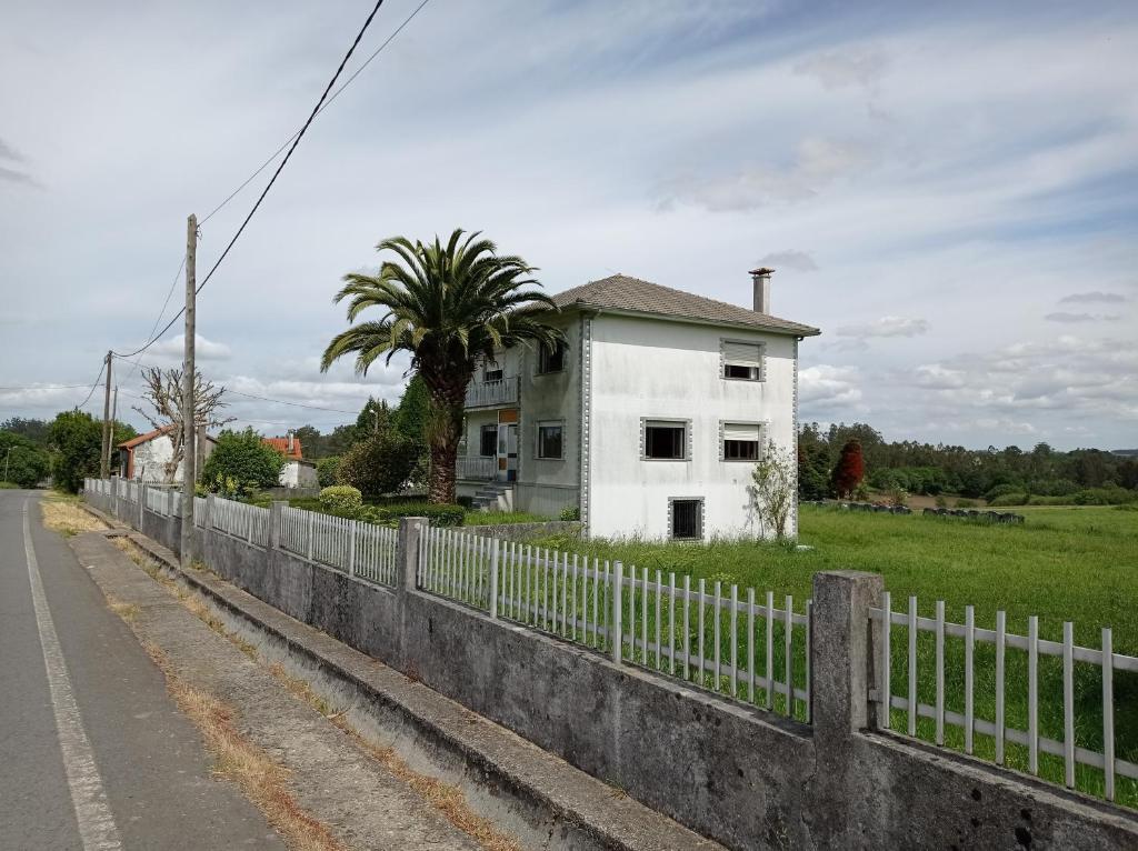 een wit huis aan de kant van een weg met een hek bij Villa Rica House in Negreira