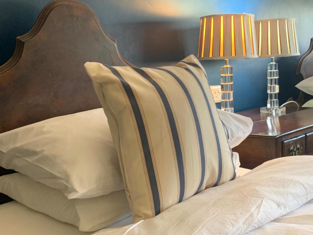 a bed with white pillows and a wooden head board at The Coast Yard B & B and Garden Chalets in Selsey