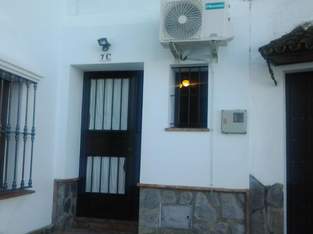 un edificio blanco con puerta y ventilador en La Casita de Zahara de la Sierra, en Zahara de la Sierra