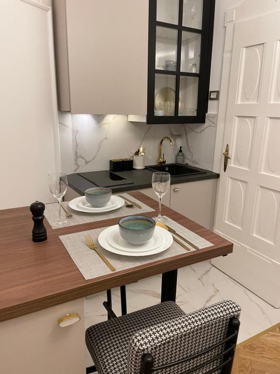 a kitchen with a table with two plates and wine glasses at Apartman Vasia Subotica in Subotica
