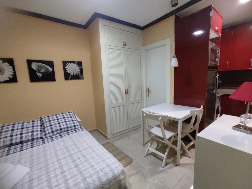 ein Schlafzimmer mit einem Bett und einem Tisch sowie eine Küche in der Unterkunft Estudio Lorenzo Acogedor in Madrid