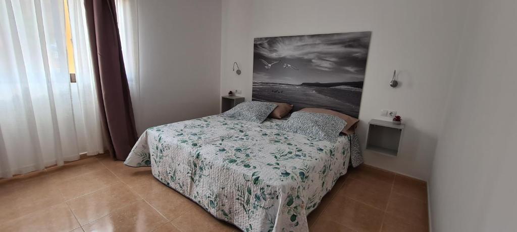 sypialnia z łóżkiem i obrazem na ścianie w obiekcie Beautiful garden flat nearly refurbished free WiFi w Corralejo
