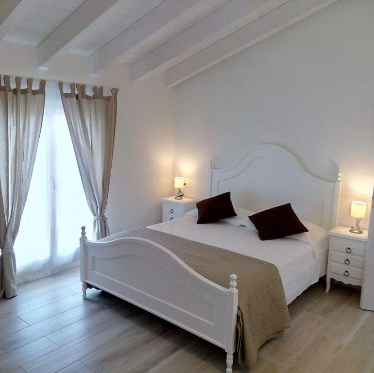 a white bedroom with a large white bed with two night stands at Casa Speri in Peschiera del Garda