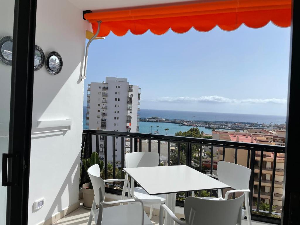 einen Tisch und Stühle auf einem Balkon mit Meerblick in der Unterkunft Achacay Sunset Apartment in Los Cristianos