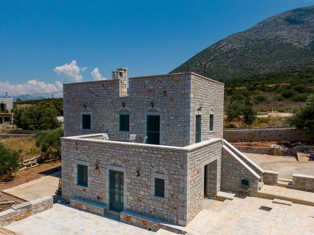 a brick building with a mountain in the background at Sugar Stone House in Pyrgos Dirou