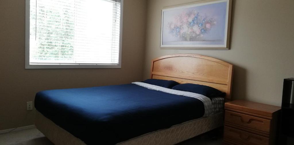 a bedroom with a blue bed and a window at San Yin Homestay private bedroom with private washroom in Calgary