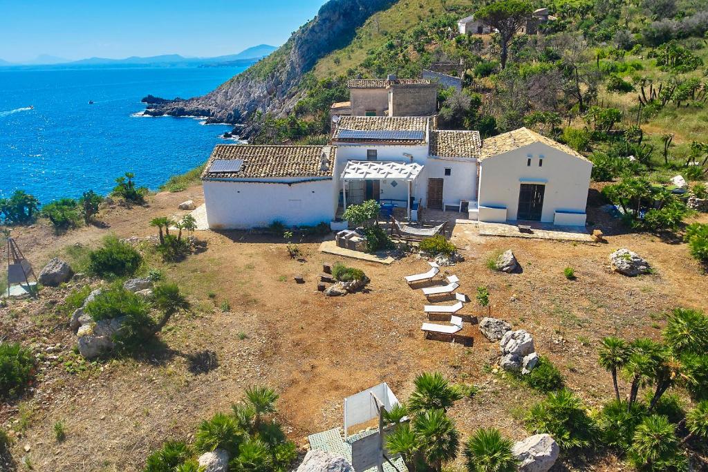 une maison sur une colline à côté de l'océan dans l'établissement Rustico Zingaro, à San Vito Lo Capo
