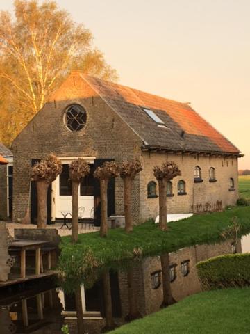 un gran edificio de ladrillo con techo naranja en B&B De Beijersche Stee, Logies aan de Waterkant en Stolwijk