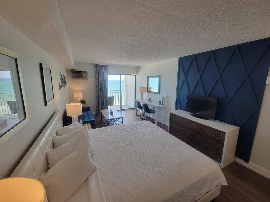 een slaapkamer met een bed en een bureau met een televisie bij Beautifully Updated Ocean Front King Suite! Sea Mist Resort 20806 - Perfect for 2-4 guests! in Myrtle Beach