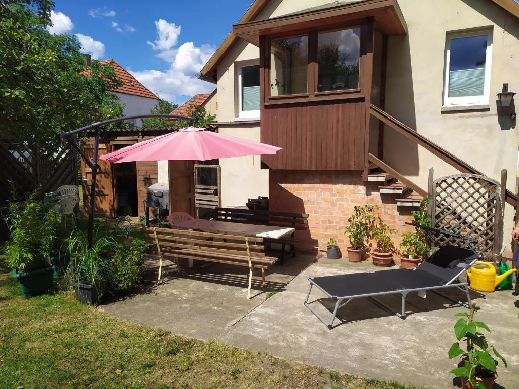 eine Terrasse mit einem rosa Regenschirm und einer Bank in der Unterkunft FeWo unter den Eichen in Wienrode