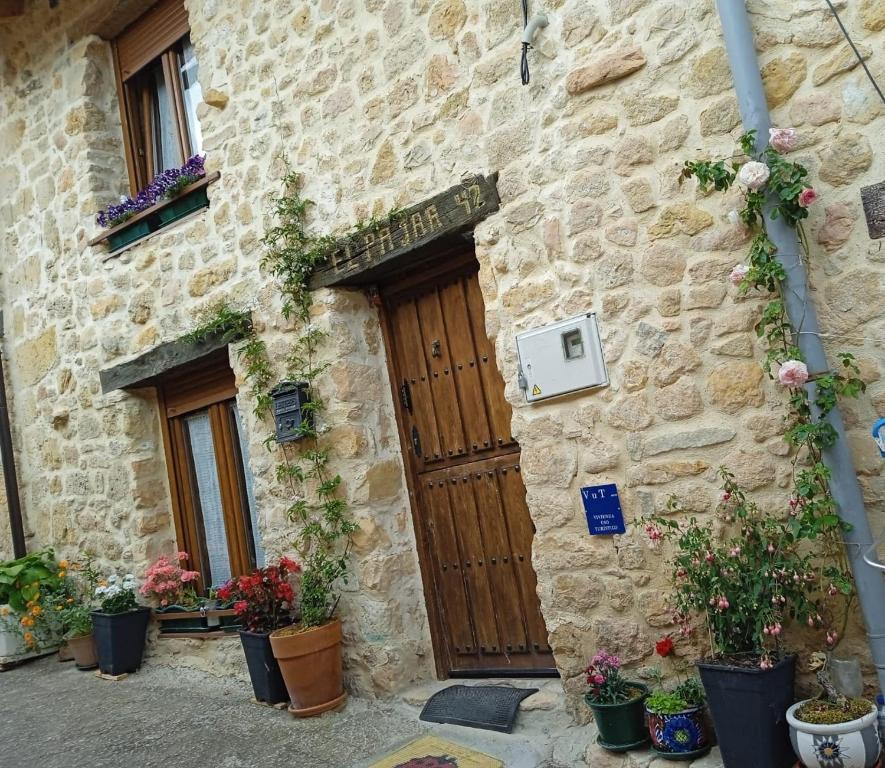 un edificio de piedra con una puerta de madera y algunas plantas en El Pajar 42, en La Aldea