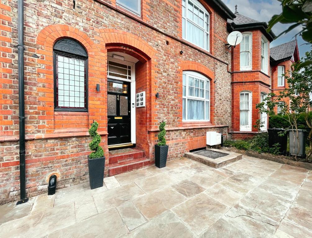 a brick building with two potted plants in front of it at Ashfield Boutique Stays in Altrincham