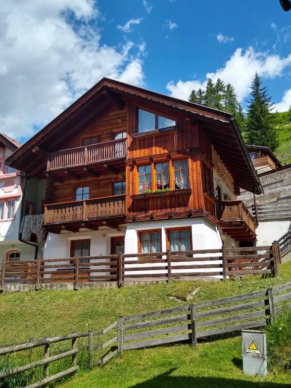 a wooden house with a fence in front of it at Appartamento Campitello House in Campitello di Fassa