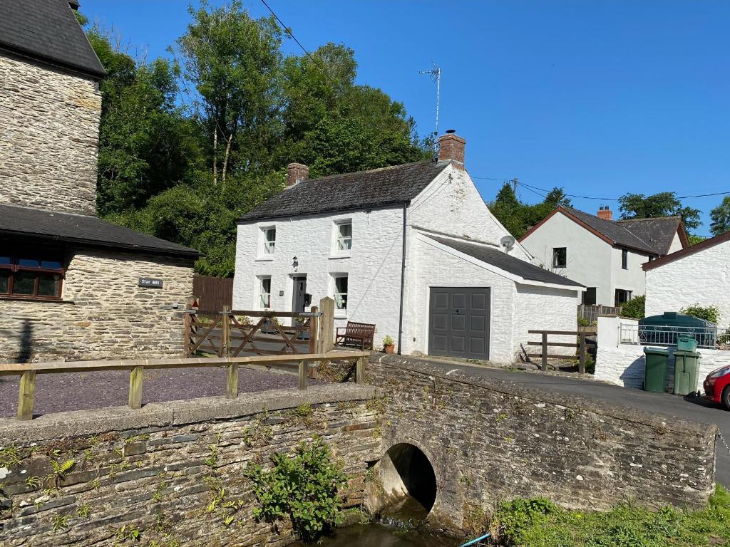 a stone wall in front of houses and a canal at Bwthyn Y Felin Star in Clydey