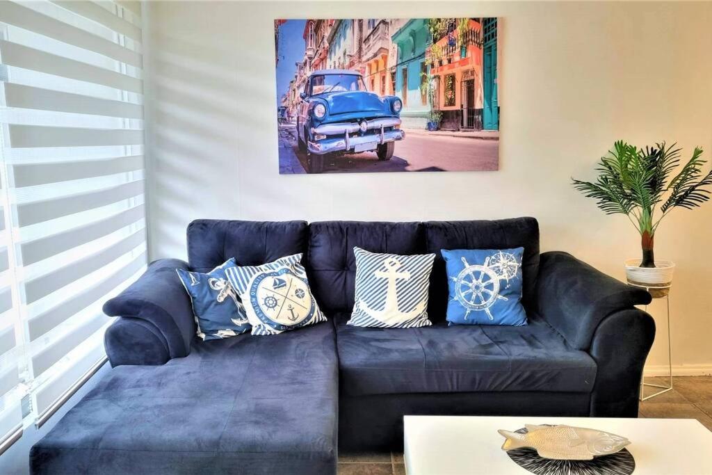 eine blaue Couch in einem Wohnzimmer mit einem Gemälde in der Unterkunft Renovado departamento a 5 min de la playa en Reñaca central in Viña del Mar