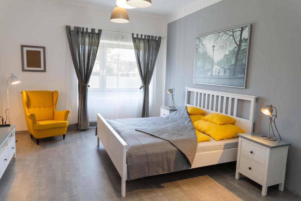 - une chambre avec un lit et une chaise jaune dans l'établissement Kunfoglalás Apartmanház, à Kisújszállás