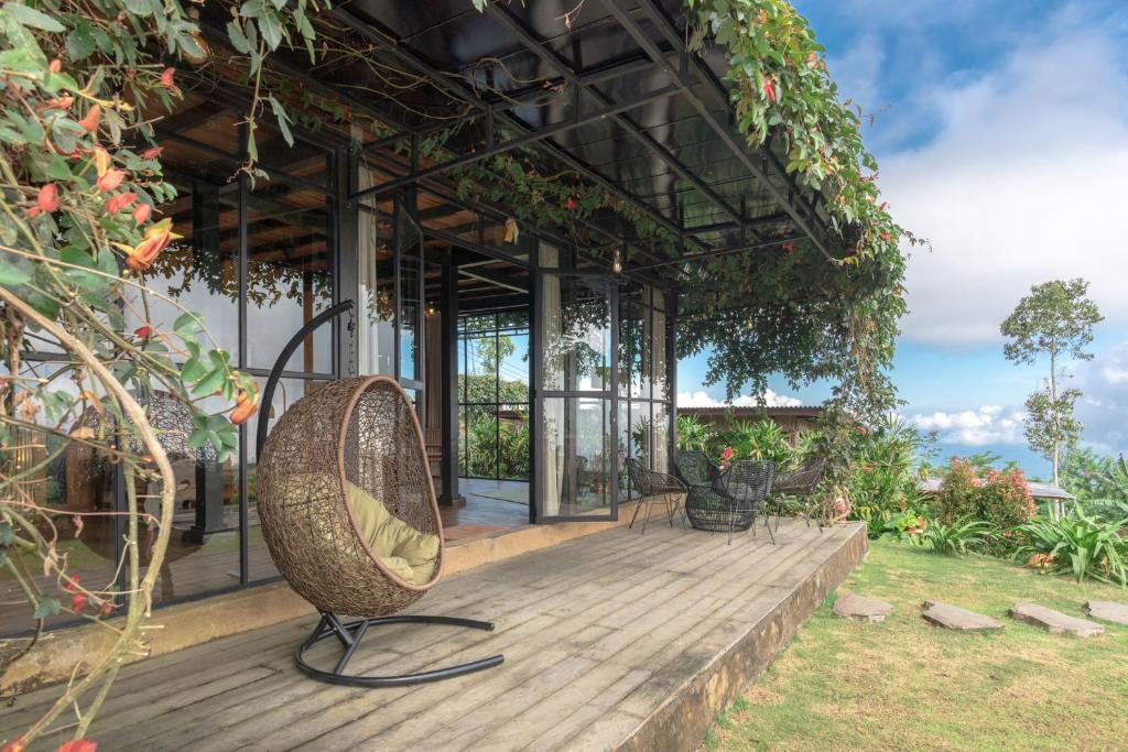 un patio con una silla de mimbre en una terraza de madera en Kayukopi en Munduk