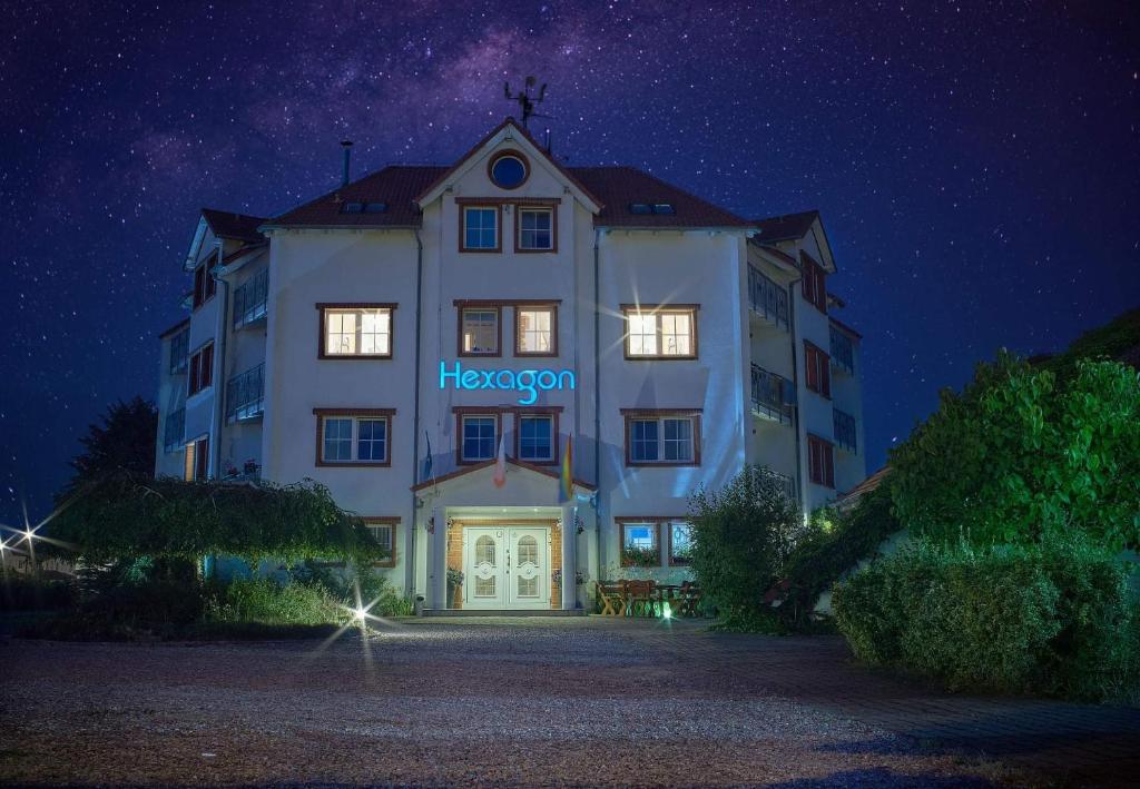 a building with a sign that reads hexagon at night at Apartamenty Hexagon nr 20 in Grzybowo
