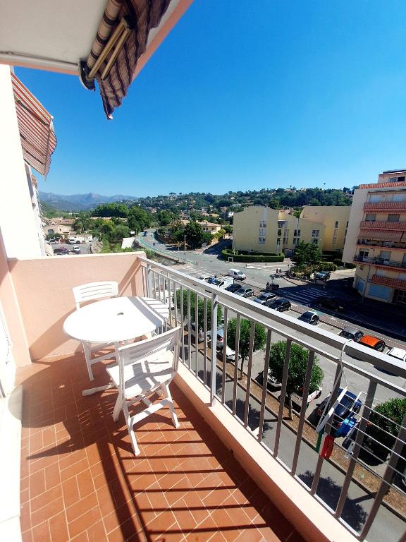 un balcon avec une table et une vue sur une ville dans l'établissement Appartement traversant avec parking gratuit et navette gratuite plage à 2 mn à pied, à Cagnes-sur-Mer