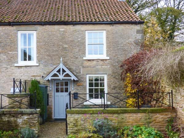 a brick house with a white door and windows at Woodside Cottage in Snainton