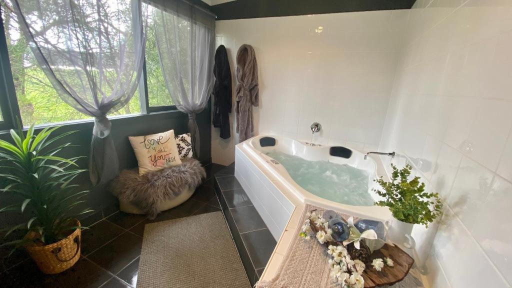 a bathroom with a tub with a chair and a plant at Couple's Resort Spa Retreat in Cowes