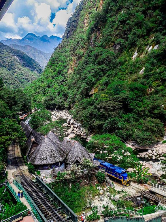 a train on tracks next to a mountain at Hotel Machupicchu Adventure in Machu Picchu
