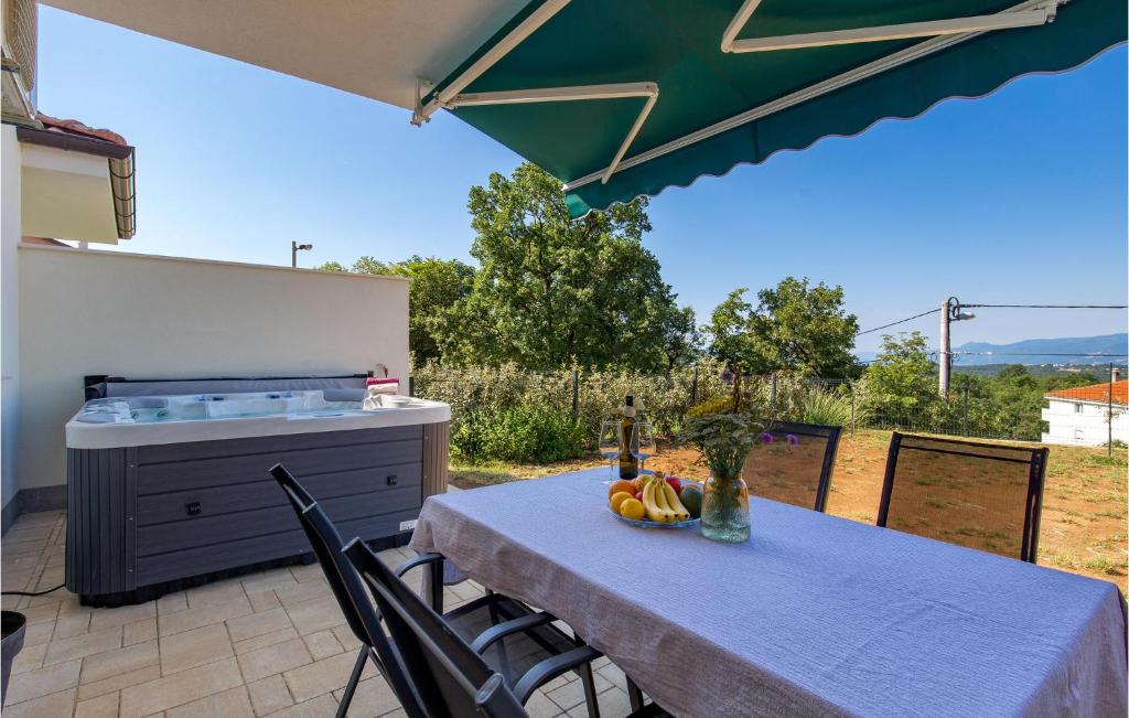 einen Tisch und Stühle auf einer Terrasse mit Whirlpool in der Unterkunft Nice Home In Marcelji With Jacuzzi, 2 Bedrooms And Wifi in Marčelji