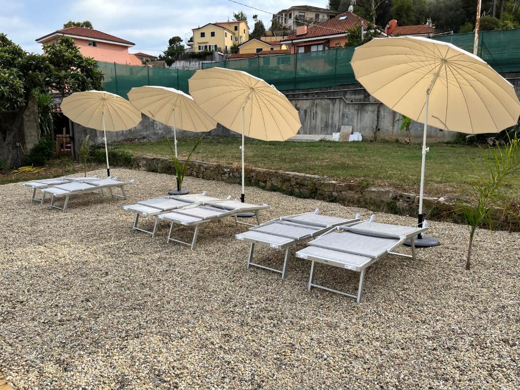 grupa stołów z parasolami na dziedzińcu w obiekcie Il Gattino di Porto - apt 4 - Monolocale terrazzo piscina w mieście Imperia