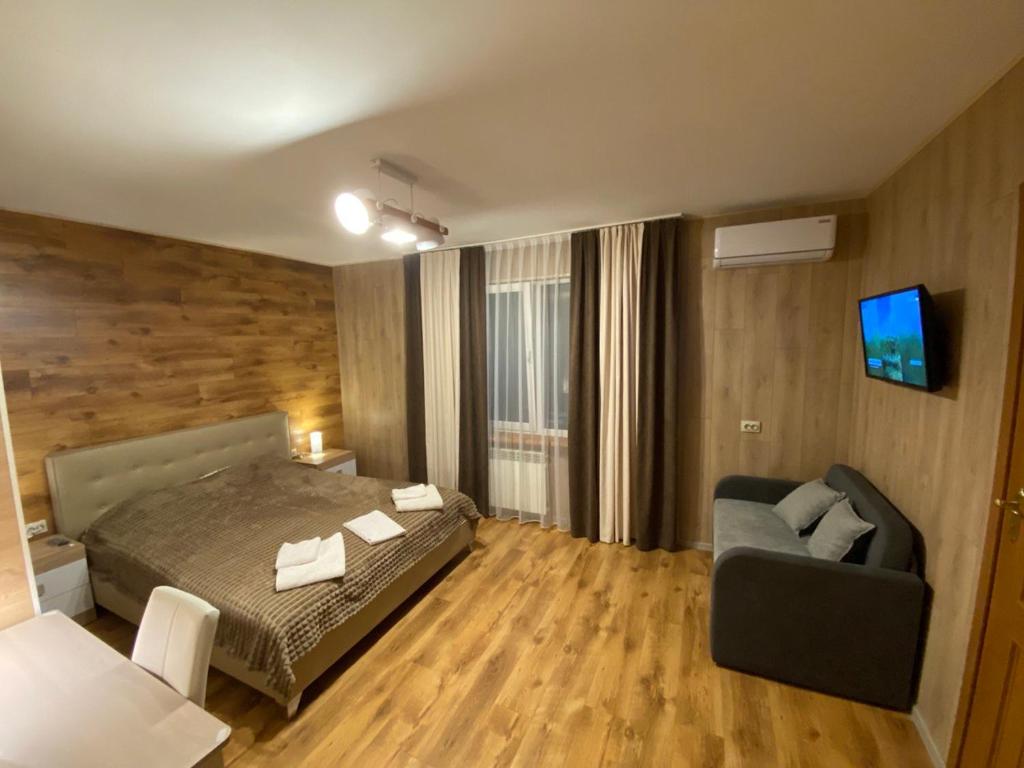 1 dormitorio con cama, sofá y TV en Кукулька міні-готель, en Slavske