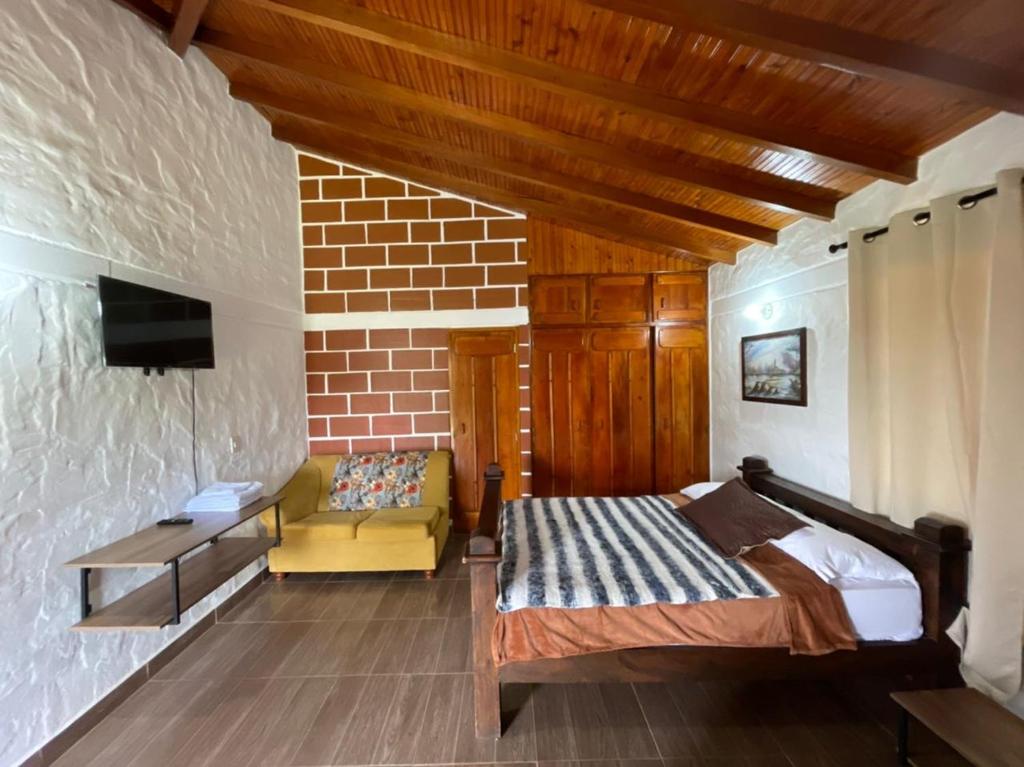 a bedroom with a bed and a couch and a tv at Finca-hotel Montecarlo Guatape by Hope in Guatapé