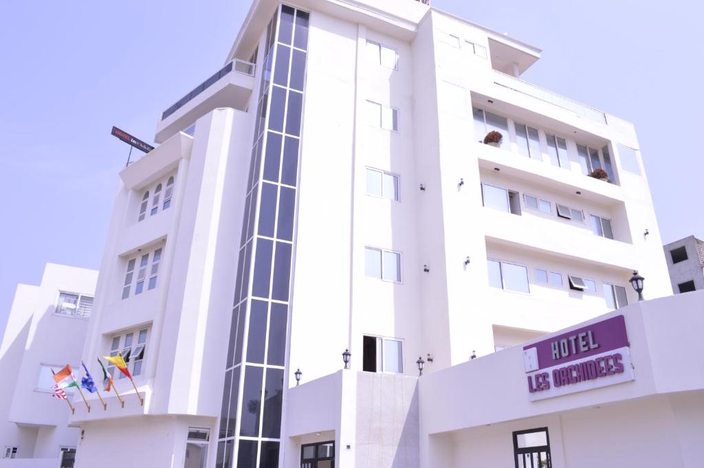 un edificio bianco con bandiere davanti di Hotel Les Orchidées a Cotonou