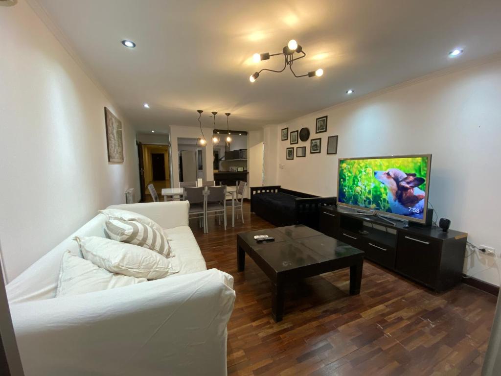 een woonkamer met een witte bank en een flatscreen-tv bij Departamento Salta Nuevo Encuentro in Salta