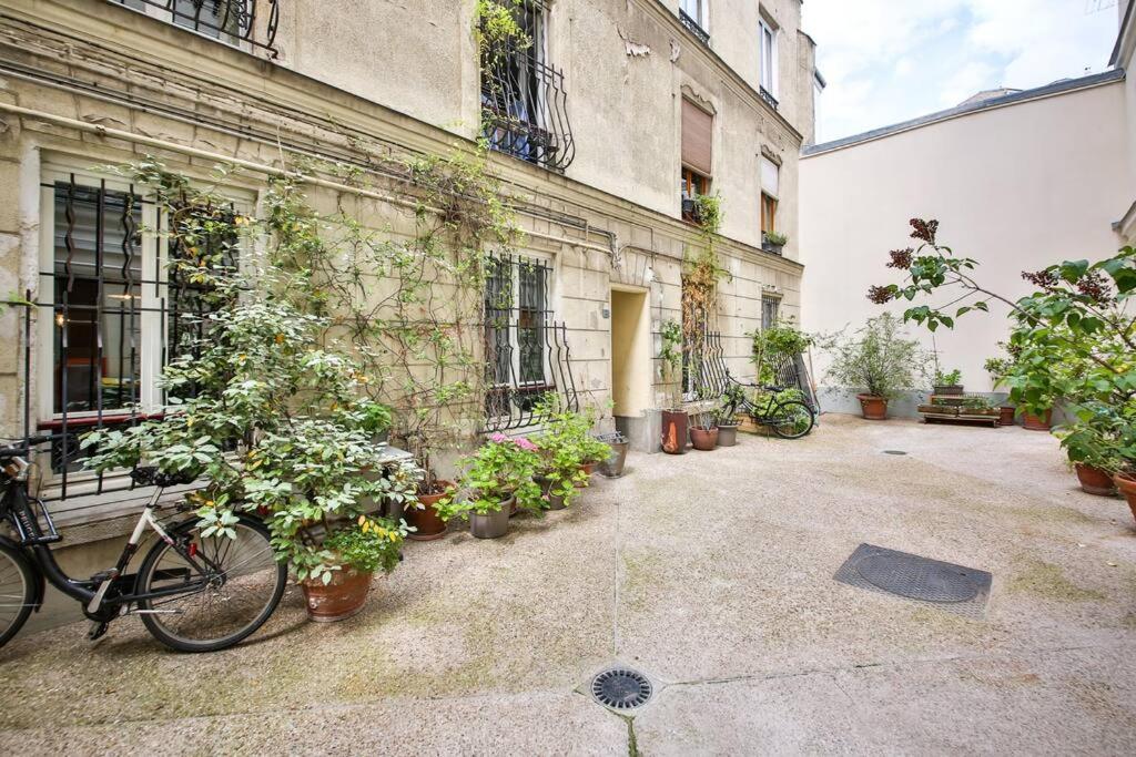 un vélo garé à côté d'un bâtiment avec des plantes en pot dans l'établissement Le Nid de Montmartre, à Paris