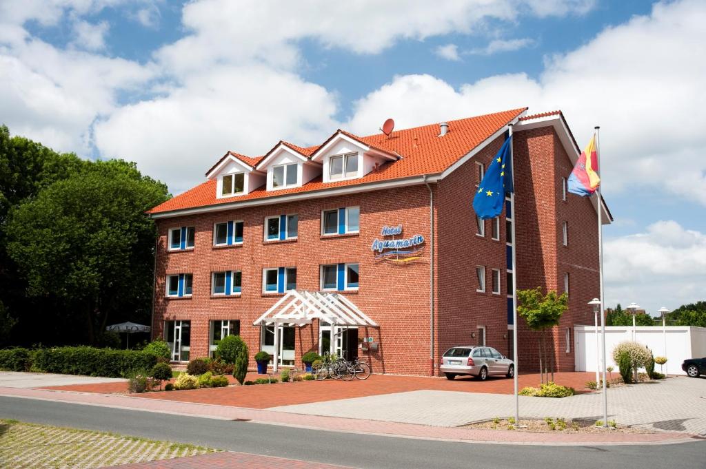 un gran edificio de ladrillo rojo con banderas delante en Hotel Aquamarin en Papenburg